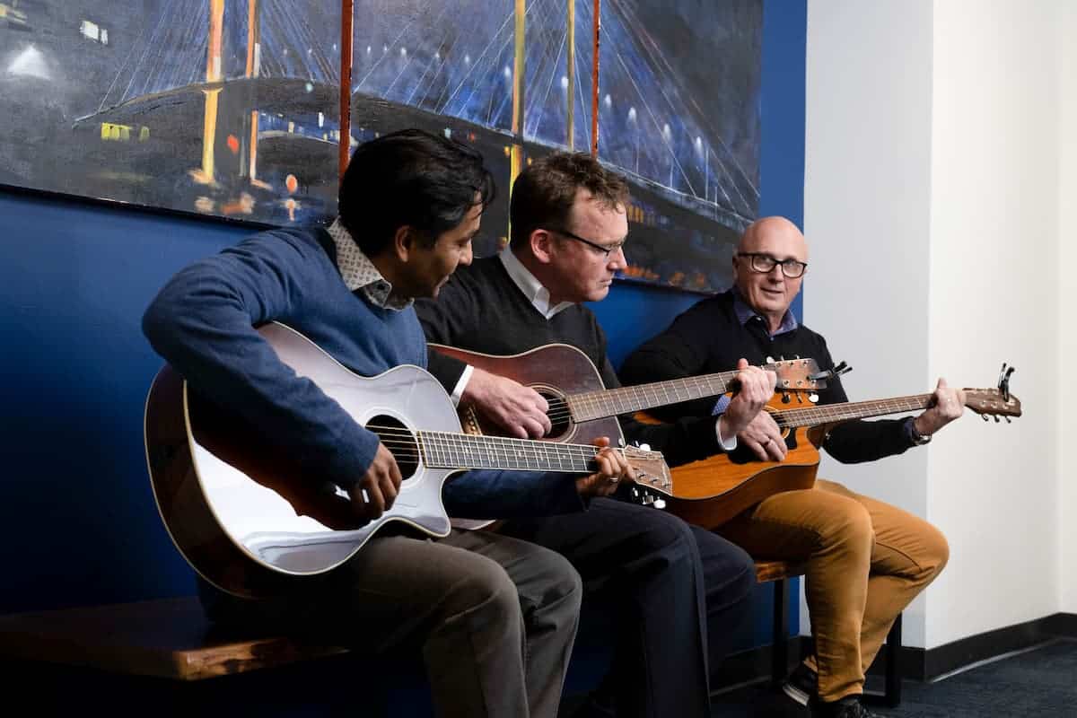 attorneys Roy Fernandes, Pat Reece, and Jim Dwyer play their accoustic guitars